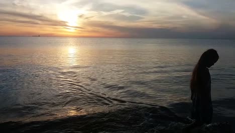 silueta de una joven caminando por la playa al atardecer