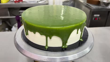 japanese matcha green tea mirror glaze drippy chiffon sponge cake spinning on revolving turntable, commercial bakery shot