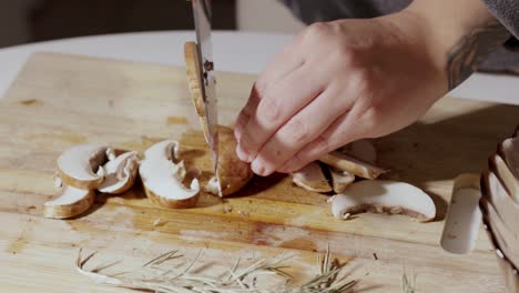 hands cut a mushroom on the wooden cutting board - close up