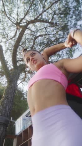 young woman stretching outdoors under a tree
