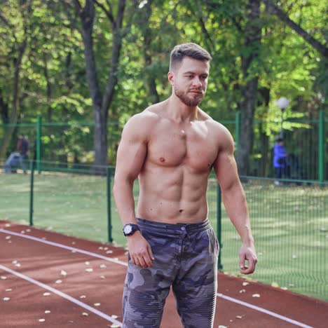 fitness young man runs at outdoor stadium. shirtless sportsman with muscular body starts running on sport track.