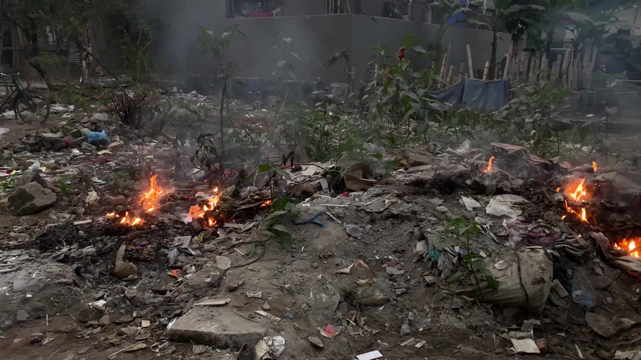 disparo de fuego que arde de la basura de las casas cercanas en dhaka, bangladesh durante el día