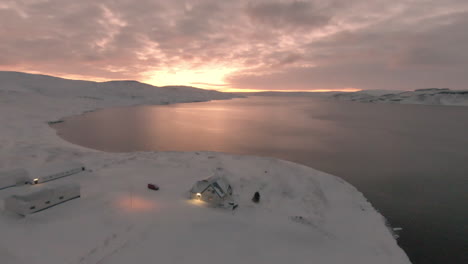 snowy icelandic farm on ocean coast during sunrise, dolly forward