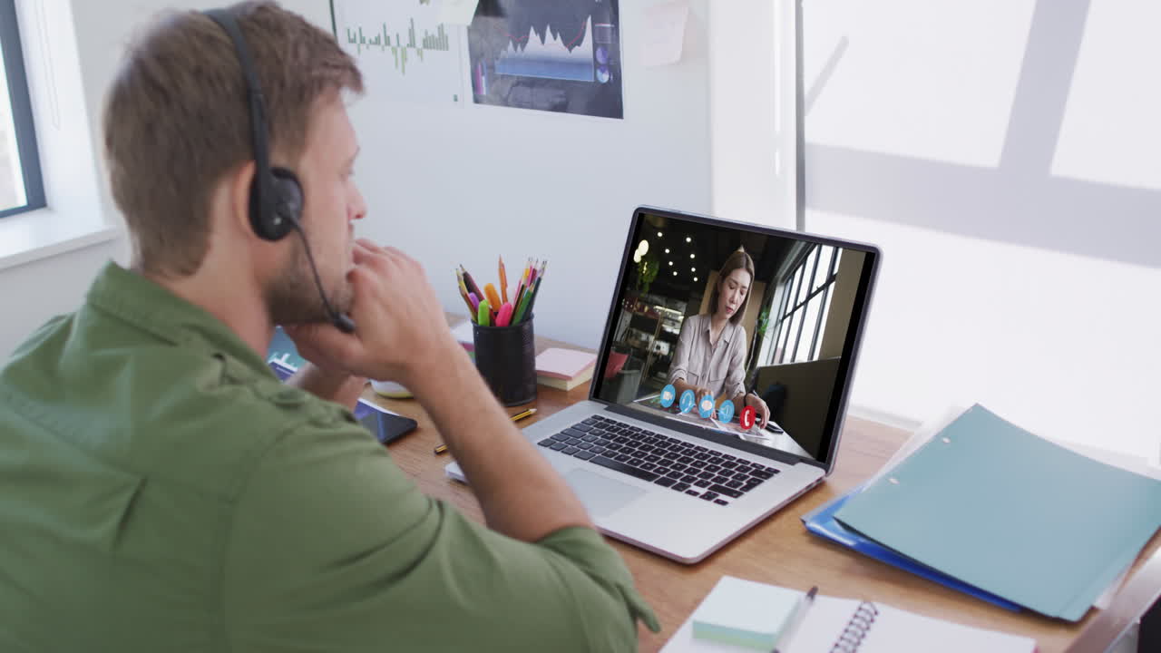 Kaukasisk mand bruger bærbar computer og telefonheadset på videoopkald med en kvindelig kollega.