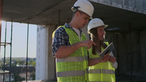 ingenieros profesionales con chalecos de seguridad y cascos que trabajan con tabletas digitales y planos