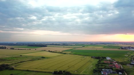 aerial over british countryside landscape with farmland and fields at sunset