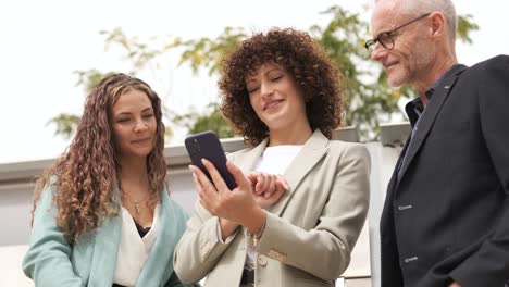happy businesswoman using cellphone while discussing with coworkers