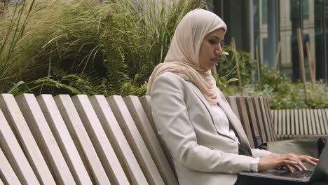 muslim businesswoman sitting outdoors in city gardens working on laptop 3