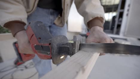 slow motion close up, cordless reciprocating straight saw cutting plank