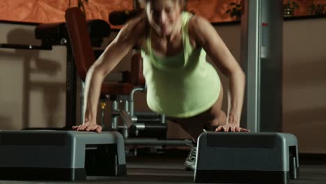 woman doing push-ups on steps in a gym