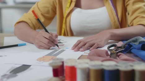cerca de la mano de la mujer diseñando ropa en el papel en el estudio