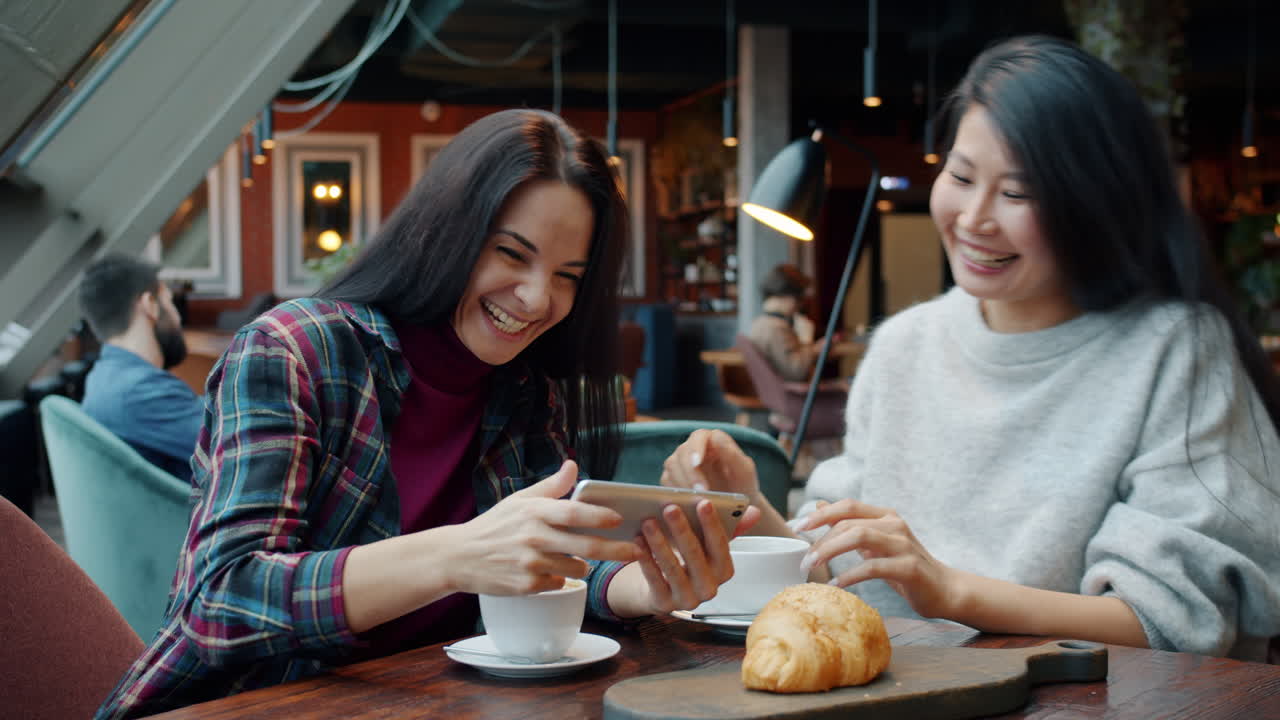 Happy friends enjoying coffee and a croissant in a cafe