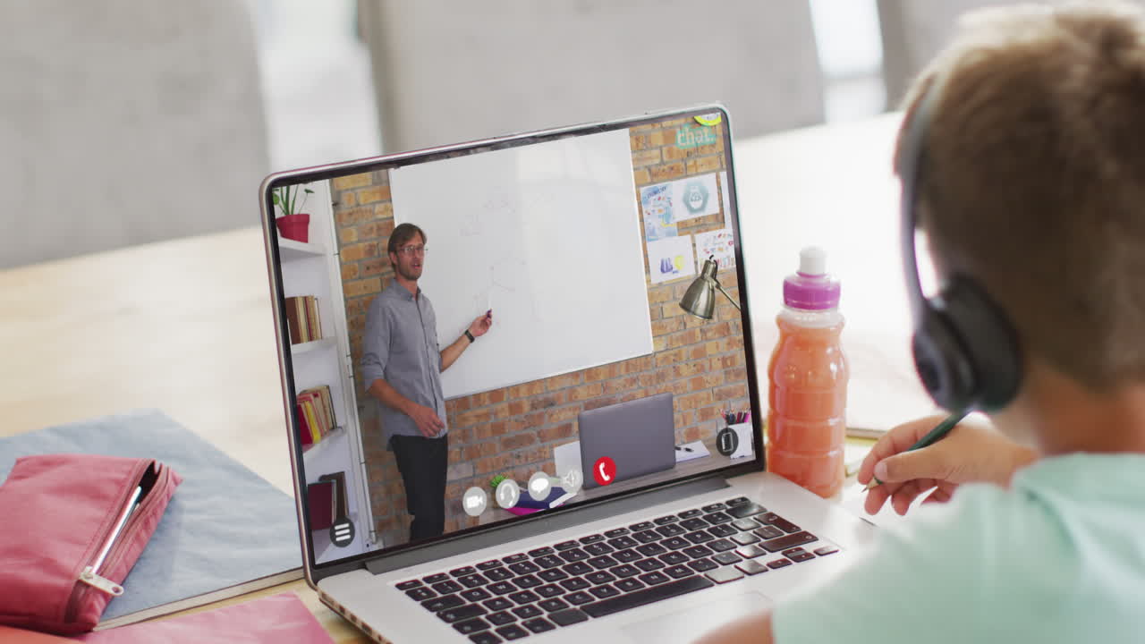 escolar caucásico teniendo clase en la llamada de video portátil con el maestro masculino en cámara lenta