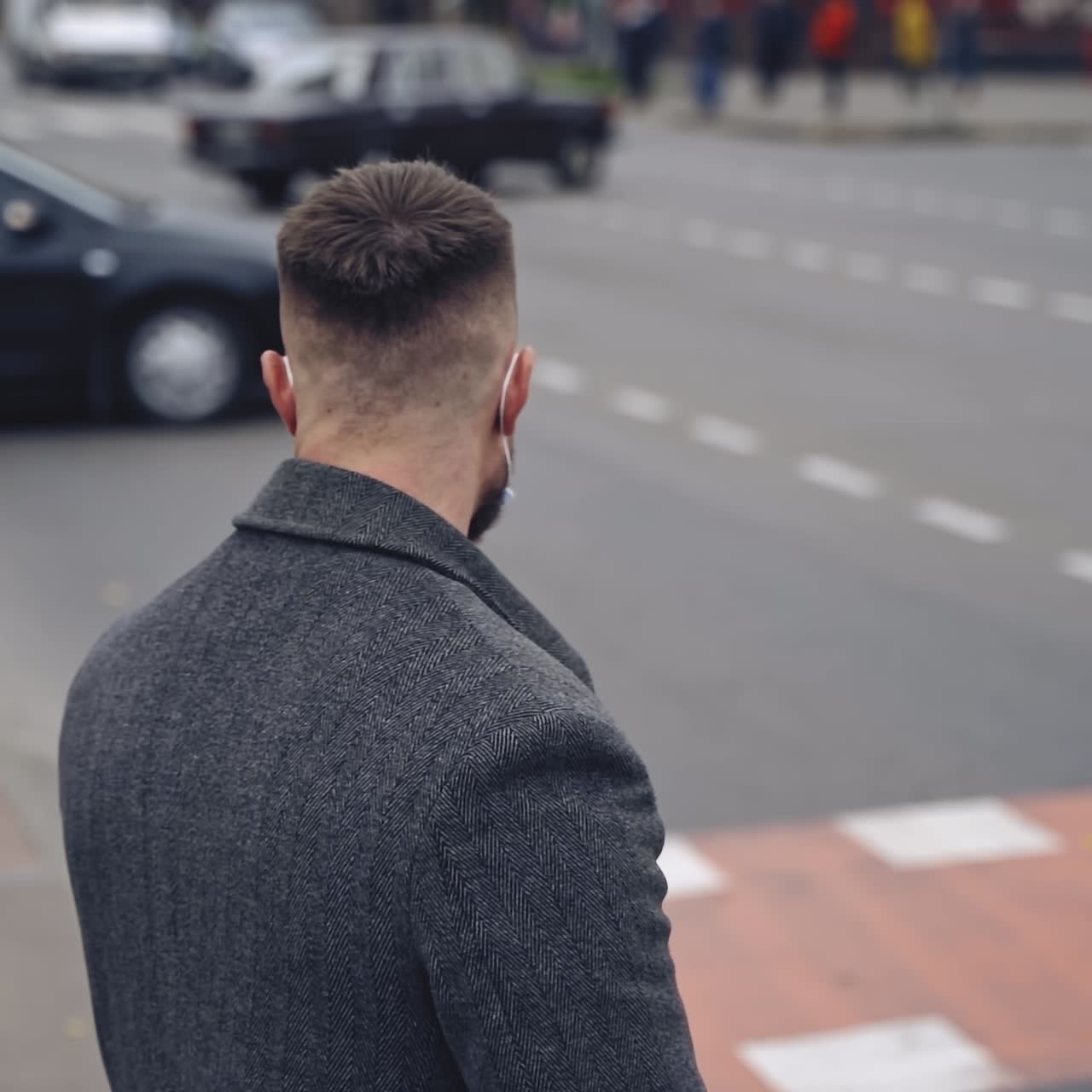 Man in medical mask outdoors. Young male wearing protective coronavirus mask on city street and looking around. N1H1 coronavirus. Slow motion.