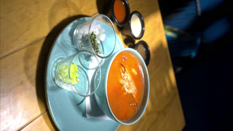 movimiento lento vertical de una sopa de mariscos con un cangrejo en ella servido en un plato azul en un restaurante tradicional mexicano