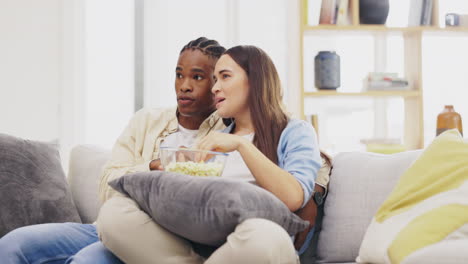 couple, watching tv and eating popcorn in home