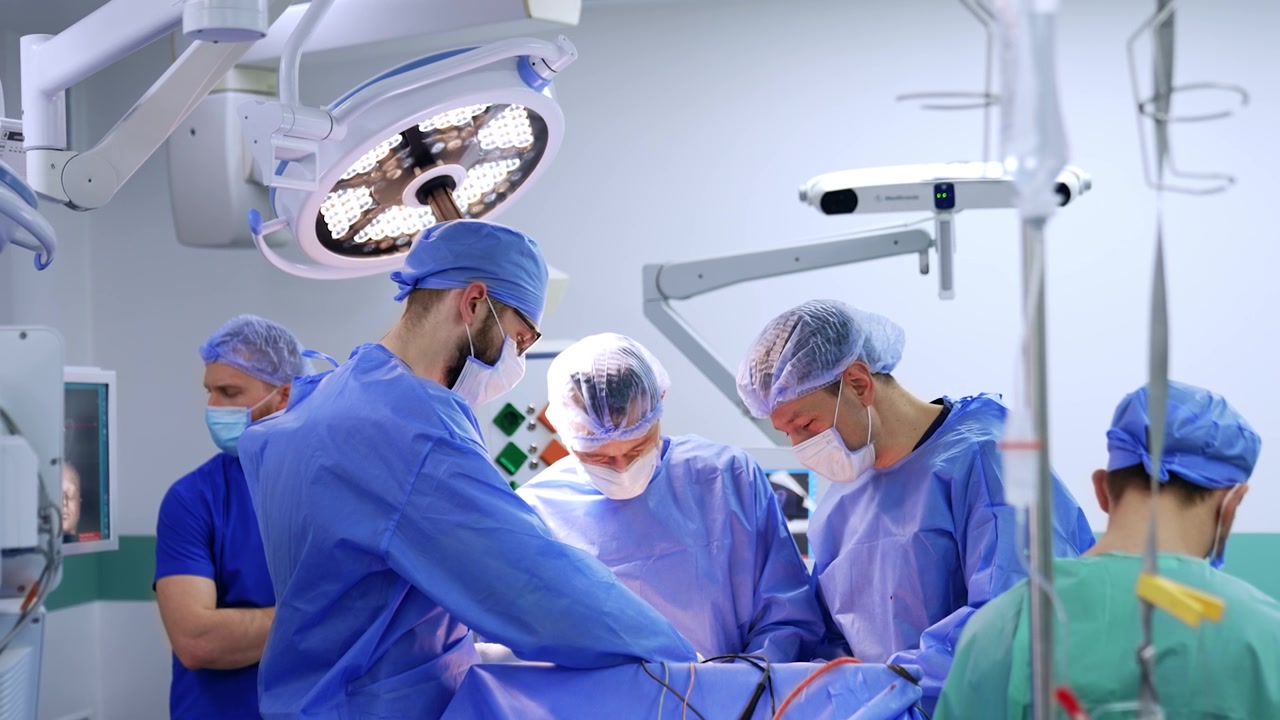 Team of neurosurgeons stands around the patient in modern surgery room. Male doctors talk at operation.