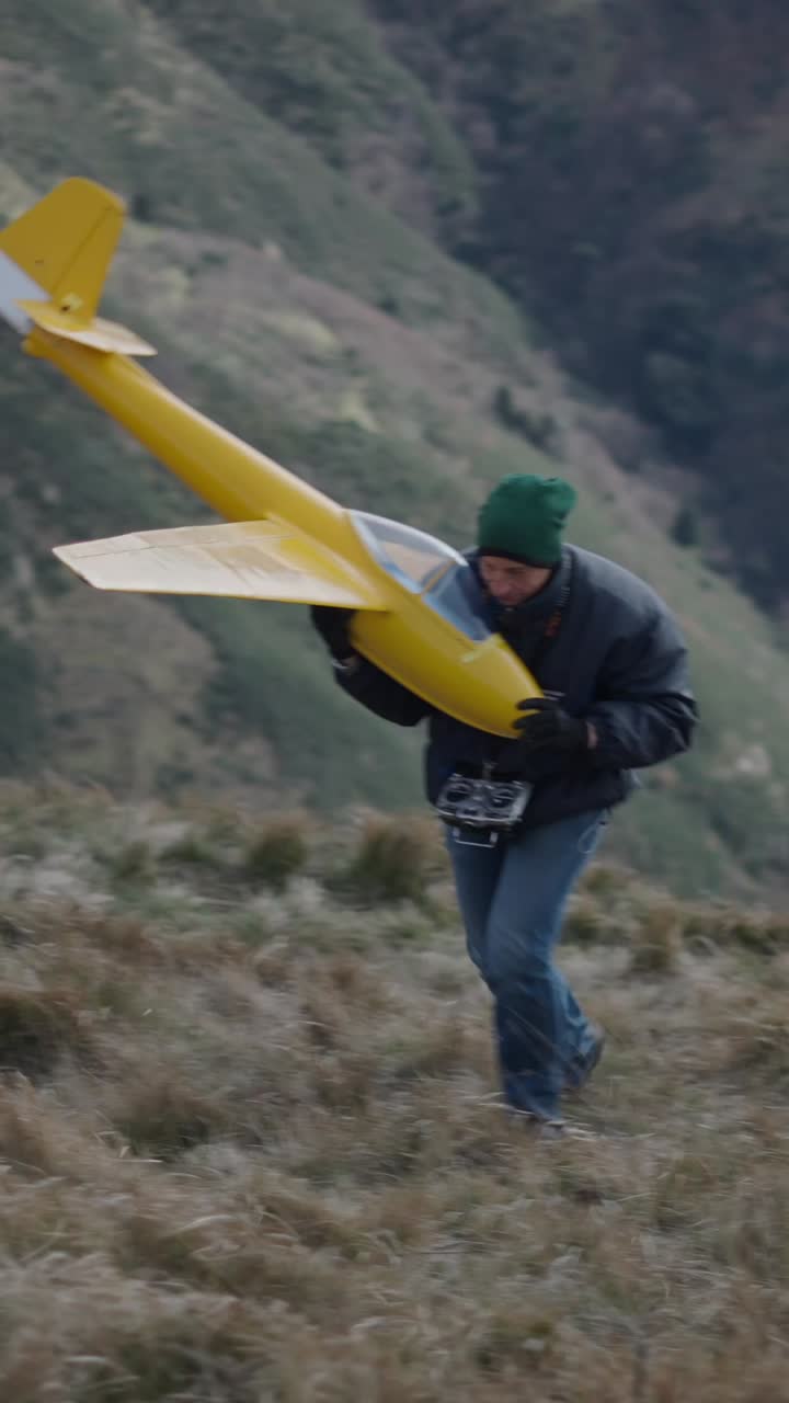 Man carrying a model airplane on a hill
