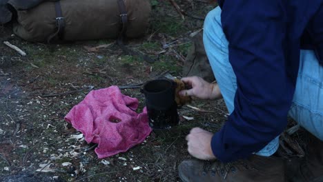 un bosquimano australiano prepara un poco de té en su porra.