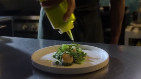 chef adds oil to plate with seafood