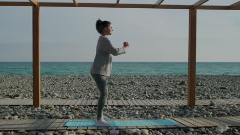 mujer haciendo sentadillas en una playa