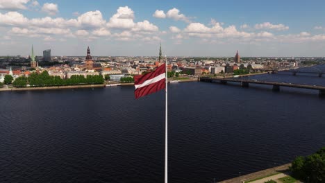 latvian flag waving in wind with riga old town in background on summer day