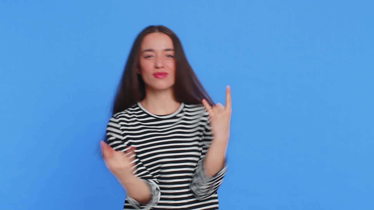 Happy woman showing rock n roll gesture by hands cool sign crazy expression dancing victory win