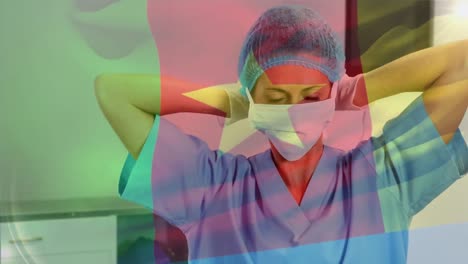 animation of flag of cameroon waving over female surgeon in operating theatre