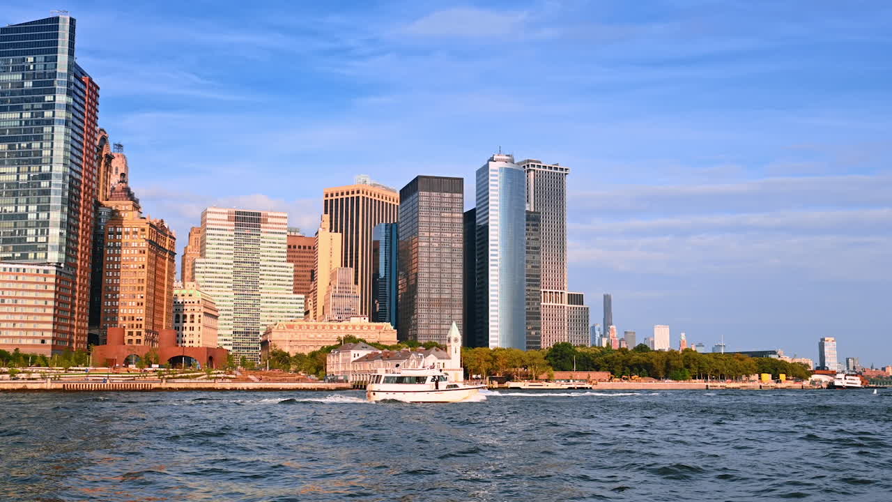 Boats move along the waterfront of New York on sunny day. Skyline of metropolis on sunny day from the riverscape