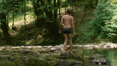 boy walking through a forest stream