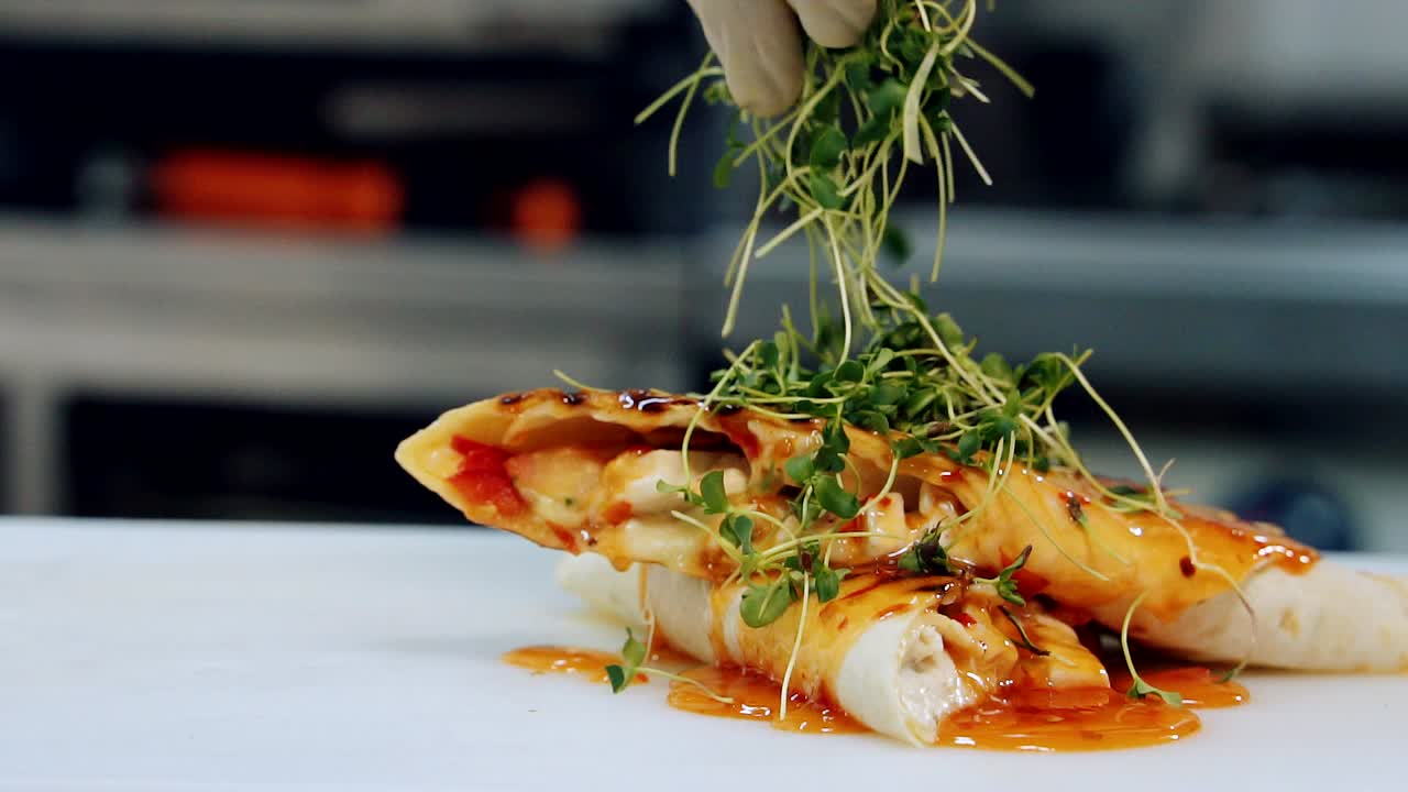 Delicious appetizer decorating with green. Chef's hand strewing pita by green sprouts before serving in the restaurant. Close-up. Slow motion