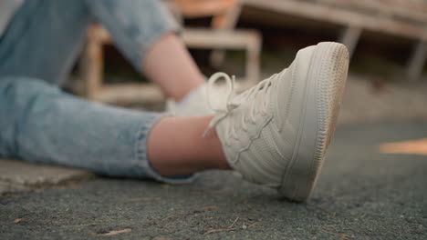 close-up of sneaker sole of seated individual with leg stretched out on ground, capturing casual, relaxed atmosphere. jeans and white sneaker create a simple, grounded vibe