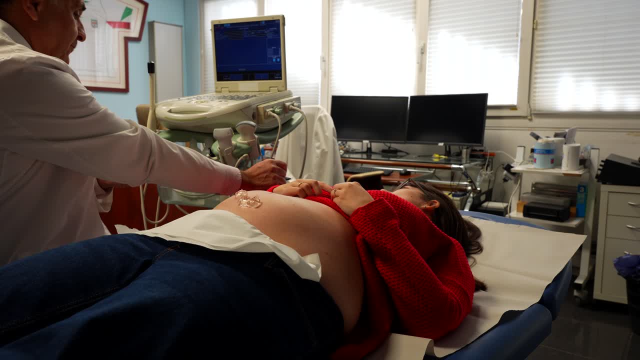 el médico se prepara para realizar una ecografía para una paciente embarazada en un consultorio médico