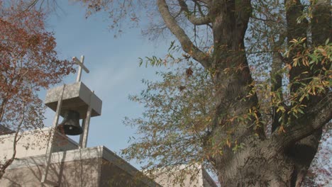 Iglesia-Exterior-Con-Campana,-Rodeada-De-árboles-Y-Hojas-De-Otoño