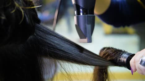 slow motion of woman's brown hair being dried and straightened
