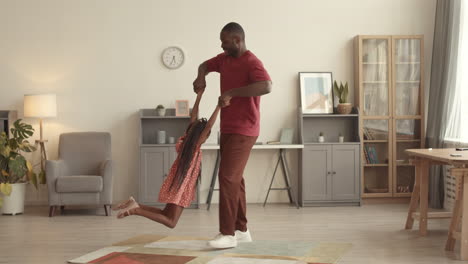 man circling daughter by arms indoors