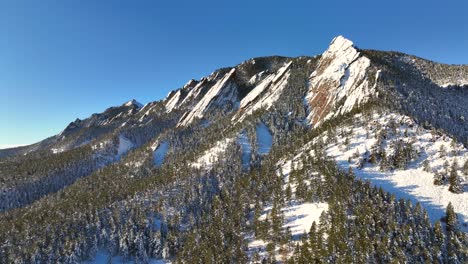 colorado natural beauty, snow capped flatiron mountains with trees in boulder, colorado on sunny winter morning