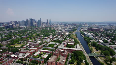 drone shot following the lachine canal, toward the skyline, summer in montreal