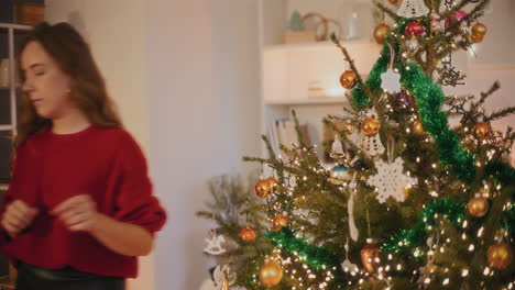 mujer atando bauble mientras decora el árbol de navidad