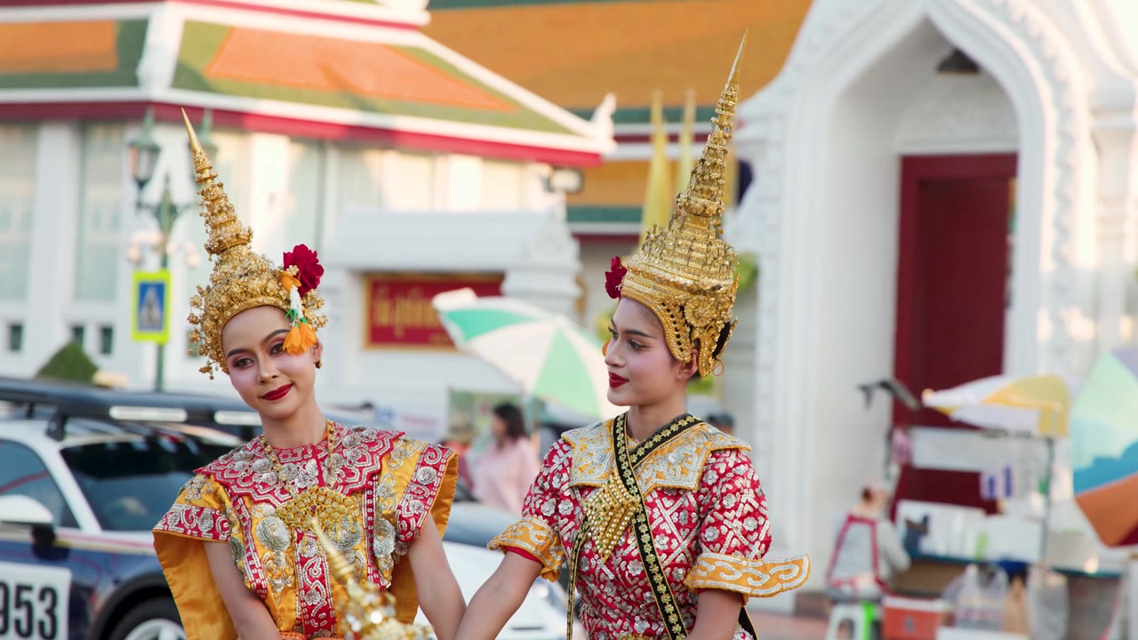 Ballerini thailandesi in sontuosi costumi dorati eseguono movimenti classici Manohra all'aperto vicino a un tempio