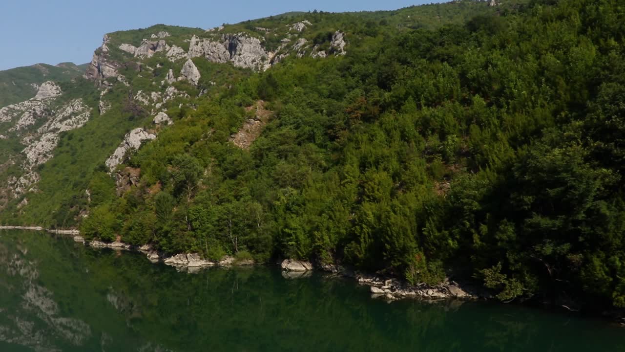 árboles verdes en las montañas que se reflejan en las aguas tranquilas del lago koman en el norte de albania
