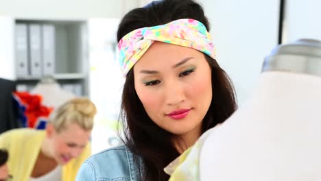 Designer-fixing-dress-with-colleagues-behind-her-smiling-at-camera