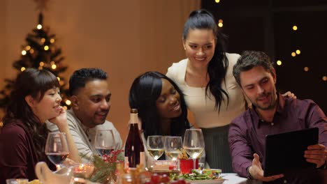 Vacaciones-De-Invierno,-Celebración-Y-Concepto-De-Personas.-Amigos-Felices-Con-Una-Computadora-Tablet-Haciendo-Una-Videollamada-En-La-Cena-Navideña-En-Casa.