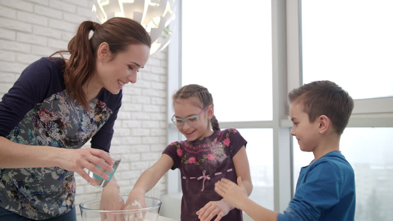 la familia se divierte en la cocina. la mujer cocina pastel con los niños.