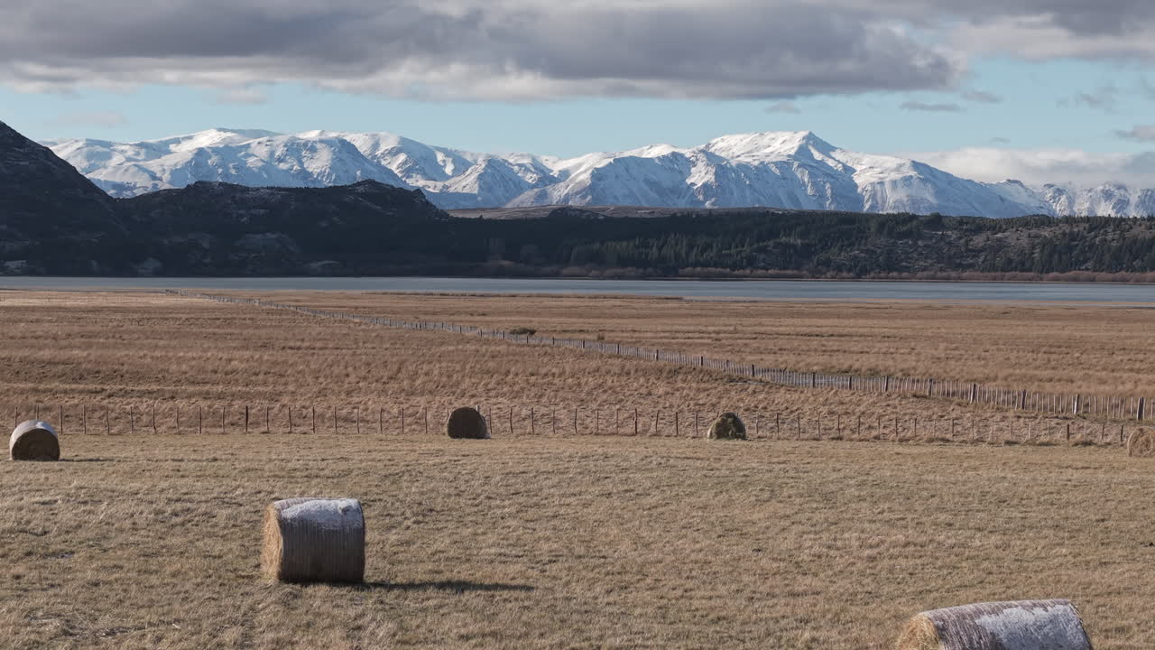 Karlı And Dağları fonuyla geniş Patagonya ovalarında yuvarlanan saman balyaları, Arjantin kırsal manzarası.