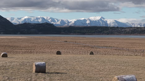 hay rolls across vast patagonian plains with snowy andes mountain backdrop, argentine rural landscape