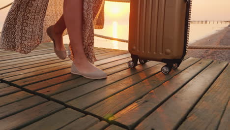 a tourist with a suitcase on the scroll came to the seaside resort and walks along the pier close-up