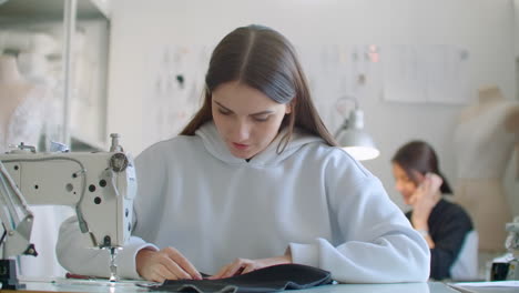 dressmaker sewing clothes. fashion designer sewing new model of clothes. seamstress woman works on sewing machine in tailoring workshop business. she stitches details for future clothing.