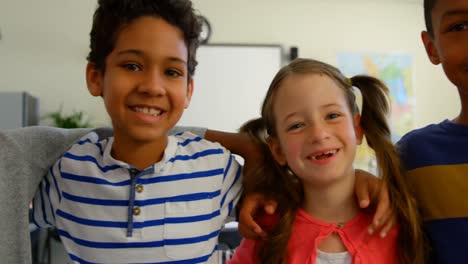vista frontal de escolares multiétnicos felices con el brazo alrededor de la clase en la escuela 4k