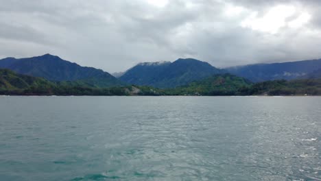 4k-Hawaii-Kauai-Bootfahren-Auf-Dem-Ozean,-Der-Von-Rechts-Nach-Links-Schwimmt,-Mit-Bergen-Und-Wolken-Mit-Bootsspray-Im-Vordergrund